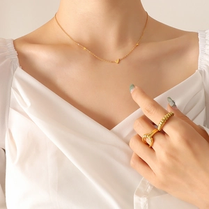 Minimalist gold plated heart necklace and spiral ring set worn with a white shirt