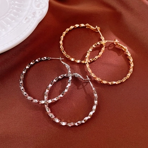 Detail of irregular geometric earrings in gold and silver finish with diamond cut texture