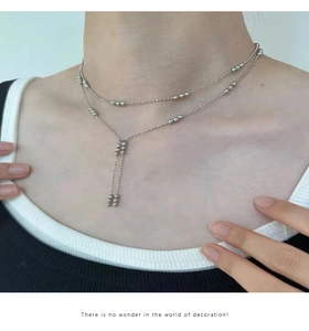 Close-up of double-layered silver bead necklace with Y-shape tassel on a model neck