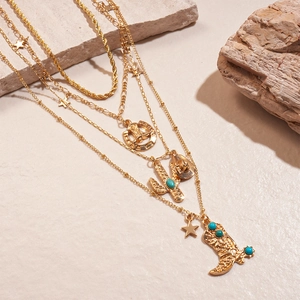 Detail of multi-layer gold necklace with western cowboy hat, cactus, and boot charms