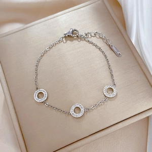 Detailed close-up of a silver stainless steel chain bracelet with three sparkling round charms