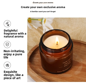Brown glass 100g scented candle on a wooden tray with a warm lit flame and daisies