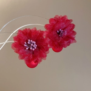 Detail of red fabric flower earrings with mesh petals and matte hanging beads