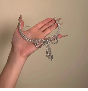 Dettaglio della collana a fiocco elegante con cristalli, perle e nappine pendenti