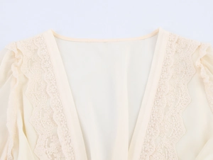 Détail du col en V d'une robe en mousseline beige élégante avec dentelle délicate