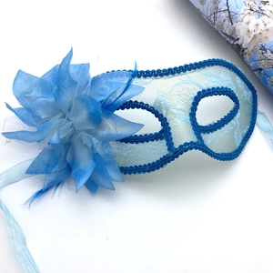 Détail d'un loup vénitien bleu en dentelle avec pétales en tissu et textures florales