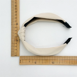 Detail view of cream fabric knotted headband with measurement rulers on white background