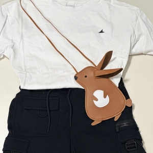 Detailed flat lay of children's brown rabbit crossbody bag with white t-shirt and shorts