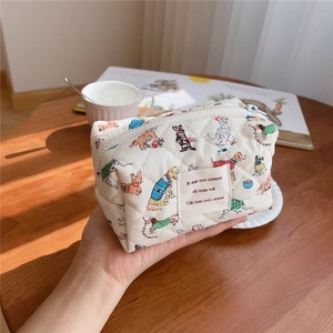 Handheld quilted cosmetic bag featuring cute cartoon dog patterns and French text