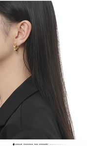 Dettaglio di orecchini a nodo in argento S925 dorato indossati con blazer nero