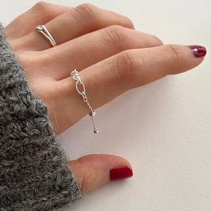 Detail of silver chain link ring and minimalist cross ring worn on model hand