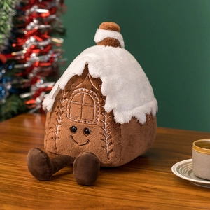 Detailed plush gingerbread house toy with white snow roof and festive embroidery