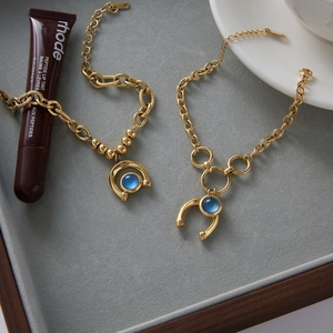 Close-up of gold titanium horse-shoe bracelets with blue resin charms on a velvet tray