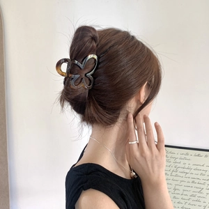 Detailed view of an elegant tortoiseshell acetate butterfly hair claw in a stylish bun