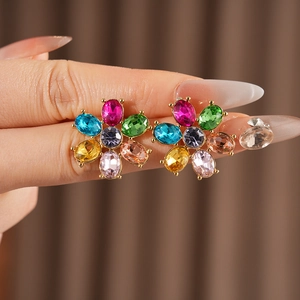 Macro view of colorful gemstone flower earrings with gold base held by hand