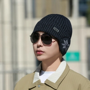 Outdoor shot of men's winter knit beanie with ear flaps and snowflake pattern