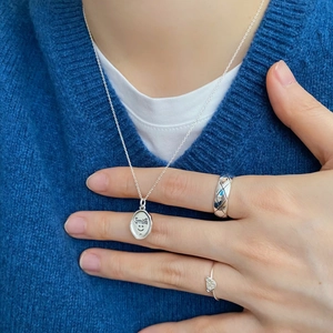 Detail of 925 sterling silver smile pendant necklace and quilted band ring on a model