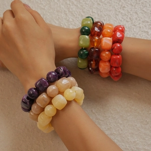 Macro detail of stacked colorful acrylic beaded bracelets with resin stone textures
