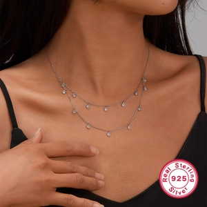 Macro shot of double-layer 925 sterling silver necklace with sparkling round zircon charms