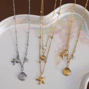 Detail view of gold and silver titanium steel necklaces with starfish and shell charms