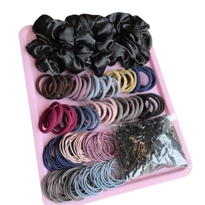 Assorted hair accessories set with satin scrunchies and elastic bands in pink tray