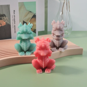 Three dragon-shaped candle molds in pastel colors displayed on a wavy wooden tray