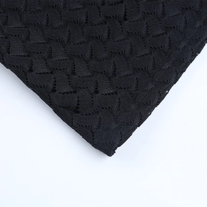 Detalle del vestido de encaje negro mostrando el bordado geométrico y la textura de punto