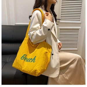 Casual yellow canvas tote bag with green Beach print shown being worn by a model