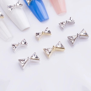 Detailed view of silver and gold metal bow nail charms with K9 crystal diamonds