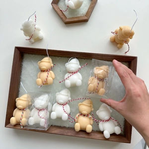 Detailed top view of handmade bear-shaped Christmas candles in wooden tray packaging