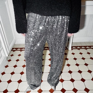 Detail of silver sequin wide leg trousers paired with high heels for a festive party look