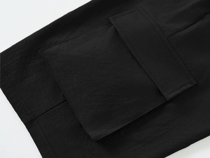 Detail of cargo short side pocket with flap design and premium stitching on black fabric