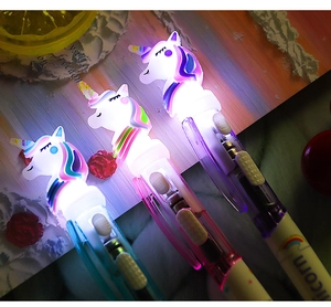 Close-up of glowing LED unicorn ballpoint pen with colorful light in a dark setting