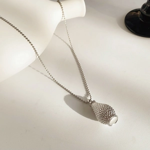 Macro detail of the silver woven basket pendant and beaded chain for the necklace