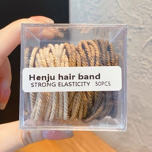 Gros plan de 50 élastiques à cheveux aux tons terre dans une boîte transparente