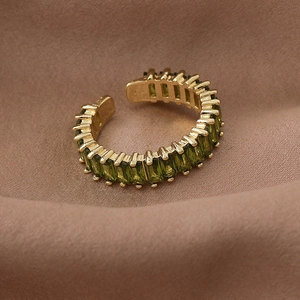 Detail of adjustable gold ring featuring emerald green rectangular crystals on satin