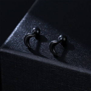 Minimalist black crescent moon stud earrings with screw back on textured jewelry box