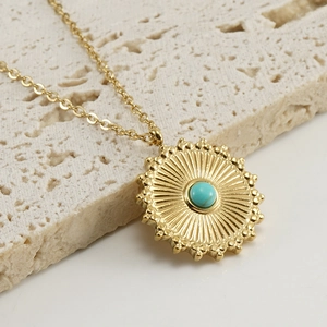 Macro detail of 18K gold-plated sunburst pendant necklace with blue turquoise center