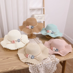 Détails de chapeaux de paille avec bords ondulés et fleurs en diverses couleurs