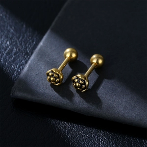 Detailed view of vintage gold rose stud earrings on a premium black leather texture