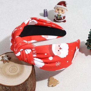 Close-up of red knotted headband with Santa Claus and snowflake patterns on a wooden base