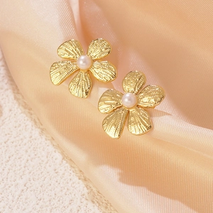 Elegant gold five-petal flower earrings with central pearl on soft pink satin fabric
