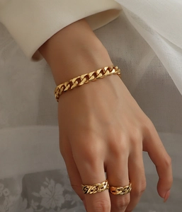 Detail of 18K gold-plated Cuban chain bracelet and matching rings on a model