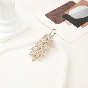 Macro shot of gold leaf hair clip with rhinestones and hollow metal leaf texture