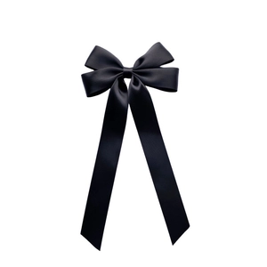 Detail of elegant black satin ribbon bow hair clip with long streamers and silk texture