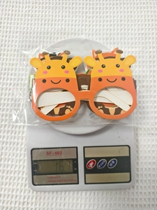 Detail of cute orange giraffe cartoon party glasses being weighed on a digital scale