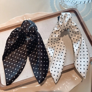 Detailed view of satin bow hair clips in black and white polka dots on a tray