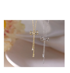 Detailed macro view of S925 silver bow necklace with dual tassels and sparkling zircons