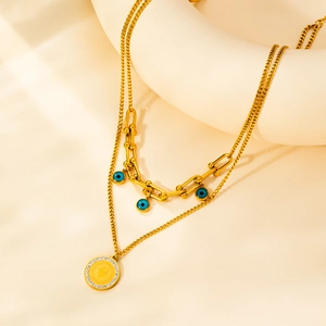 Dettaglio della collana a strati in titanio dorato con ciondoli evil eye e moneta