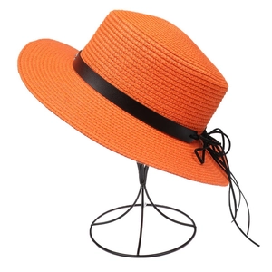 Close-up of orange straw sun hat with black leather band on a metal display stand